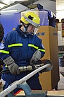 Eine Helferin durchtrennt mit einer hydraulischen Schere ein eingespanntes Metallrohr